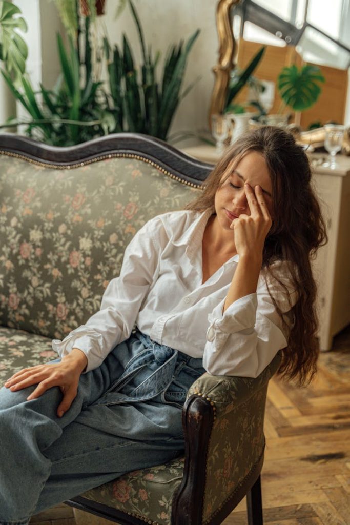 Crafting Captivating Headlines: Your awesome post title goes here A woman relaxes on a floral vintage sofa in a cozy, light-filled room with plants.
